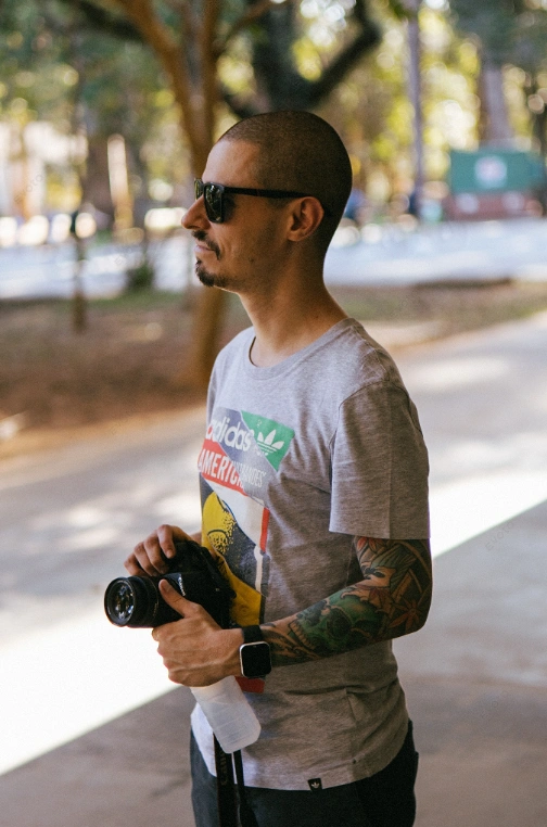 Caio Monticelle de perfil segurando uma câmera fotográfica