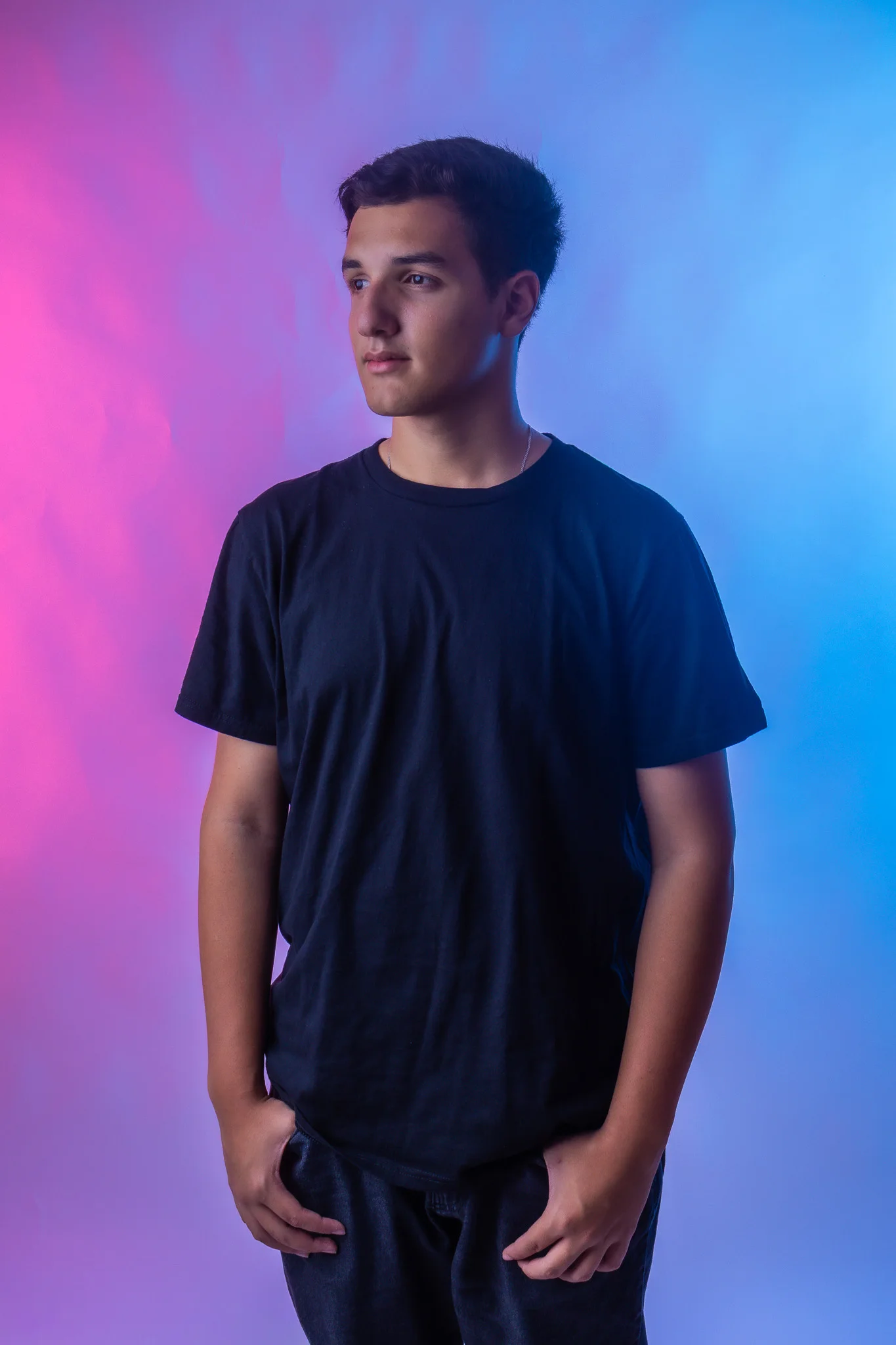 Vinicius em pé diante de um fundo iluminado em rosa e azul
